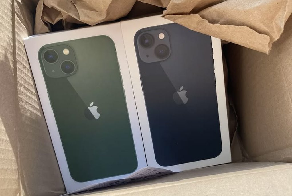 Caixa de papelão com dois celulares lacrados, um verde e um preto